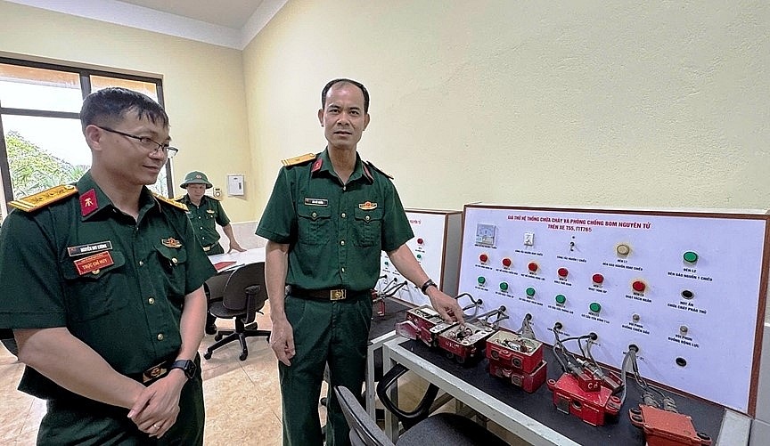 Thiếu tá quân nhân chuyên nghiệp Bùi Đức Ngừng giới thiệu với Thượng tá Nguyễn Huy Cương, Giám đốc Xưởng X1 về sáng kiến “Giá thử hệ thống chữa cháy và phòng, chống bom nguyên tử trên xe T-55 và PT-76B”. Ảnh: THÁI KIÊN